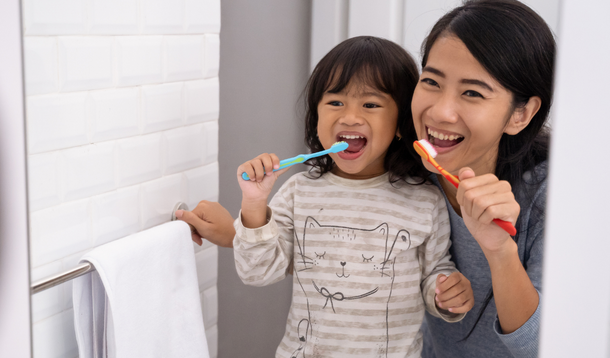 Mom and daughter brushing teeth together