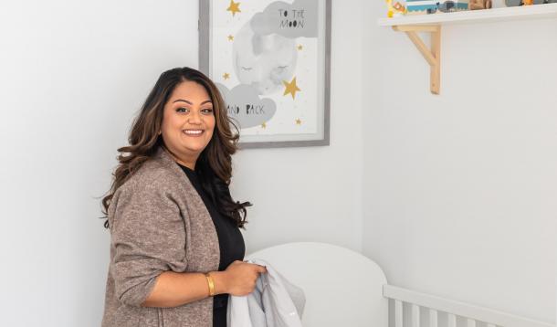 Mom folding blanket in nursery while smiling directly at the camera