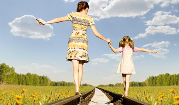 mother and daughter balancing on train tracks