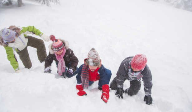 Four children bundled up in snow suits playing in the snow