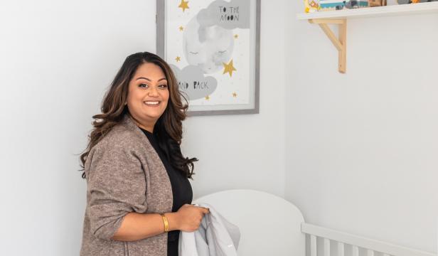 Mom folding blanket in nursery while smiling directly at the camera
